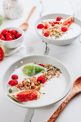 Granola with yogurt, figs and raspberries in bowls