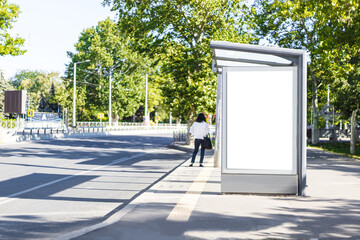 Blank white mock up vertical light box at bus stop during the day on a sunny day