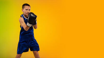 Fototapeta na wymiar Competitive. Teenage professional boxer training in action, motion isolated on gradient background in neon light. Kicking, boxing. Concept of sport, movement, energy and dynamic, healthy lifestyle.
