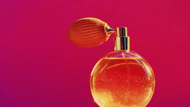 Golden fragrance bottle and shining light flares on pink background, glamorous perfume scent as holiday perfumery product for cosmetic and beauty brand, stock footage