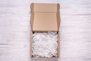 Shredded paper filler in cardboard box on wooden table