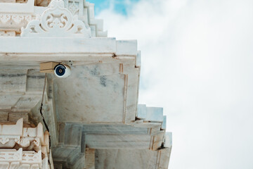 Close up shot of CCTV camera on wall of Temple against cloudy sky. with space for text