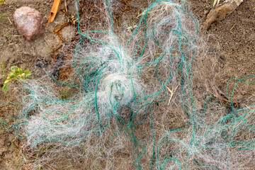 torn fishing net on the river bank