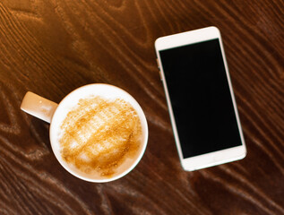Coffee mug and mobile phone on the table in the cafe top view
