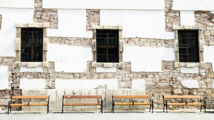 Empty wooden benches in front of an old stone wall, Budapest, Hungary