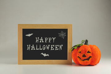 Happy Halloween written on a Chalkboard and fake Curved pumpkin - halloween background