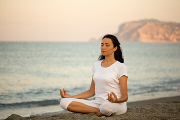 Fototapeta na wymiar Yoga concept. Female practicing yoga at the beach. Negative space.