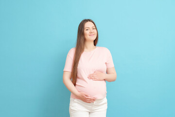 happy young pregnant woman in pink t-shirt on blue background