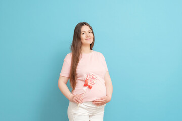 happy young pregnant woman in pink t-shirt on blue background with candy in hand, sweet tooth
