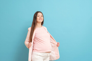 funny young pregnant woman in pink t-shirt on blue background, woman cannot wear clothes, small clothes