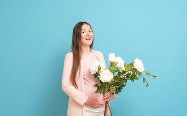 happy young pregnant woman in pink t-shirt on blue background holding a bouquet of flowers