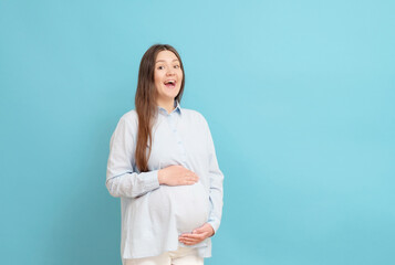 young pregnant woman on blue background in blue clothes