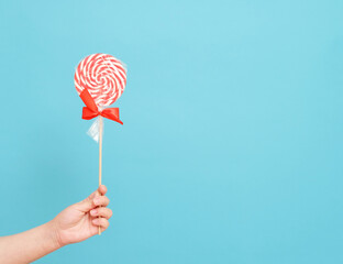 candy cane in hand on blue background