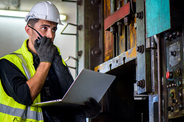 Caucasian engineer mechanic man checking for maintenance pressing metal machine by laptop at factory, worker at industrial concept