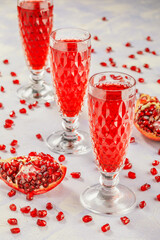 three glasses with pomegranate juice on background with sliced pomegranate and seeds
