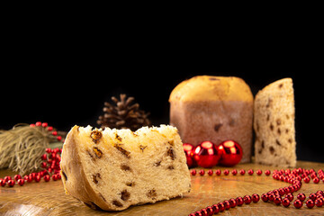 Arrangement with panettone, pine cones and Christmas balls on rustic wood, black background, selective focus.