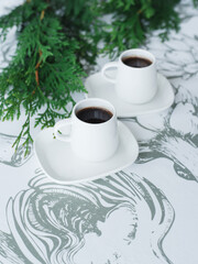 2 cups of coffee on the table, thuja twigs
