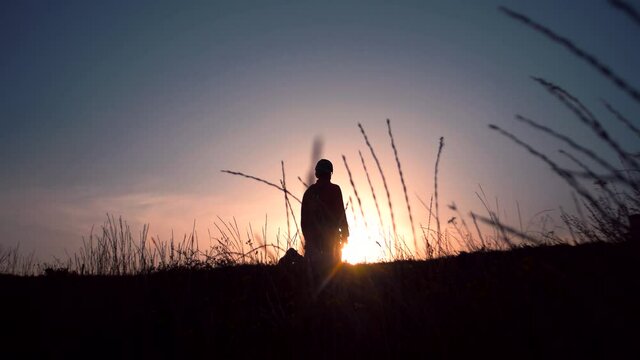Silhouette of a man falling to his knees in the sunset light