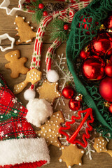 Christmas decorations lie on a light brown wooden background. Layout of Christmas toys in a string bag, cookies, snowflakes, santa hat