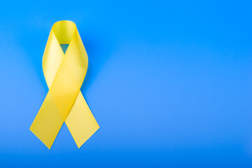 Yellow ribbon on blue background. Cancer concept