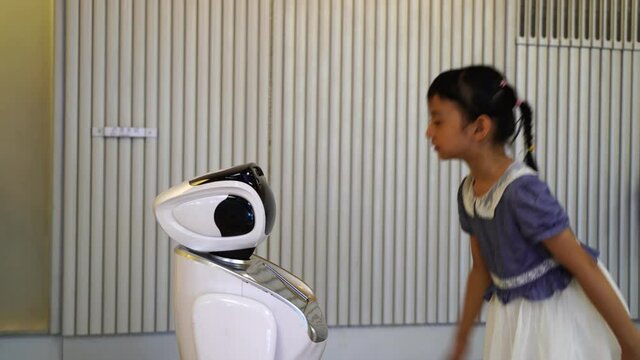 asian child extends a hand to the robot. concept of friendship between the robot and child