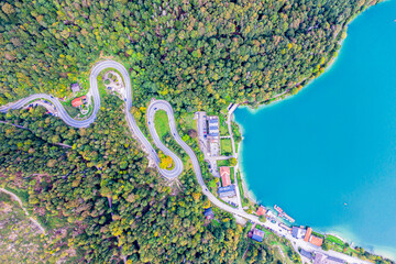 Winding Road surrounded by a colourfull trees in the forest. Aerial drone view. Kesselberg
