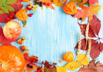 Pumpkin and autumn oak and maple leaves, apple and ears of wheat on blue wooden background. Thanksgiving day or Halloween concept. Flat lay with copy space.