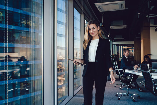 Happy Caucasian female entrepreneur dressed in formal outfit holding modern touch pad connected to 4G, half length of successful business woman with digital tablet looking at camera and smiling