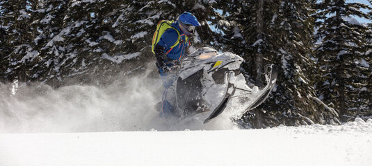 riding a mountain snowmobile in a high - altitude forest. Extreme snowmobilers Ride & Racing. a bright suit and a snow motorcycle. snow bike sports riding. Winter fun moto extreme. high res photo