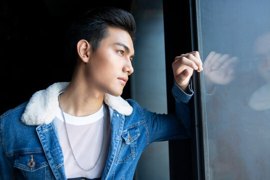 Handsome young man posing on vintage dark  background. Portrait of satisfied Asian man against  wall. Close up face of fashionable Asian man on wall background.