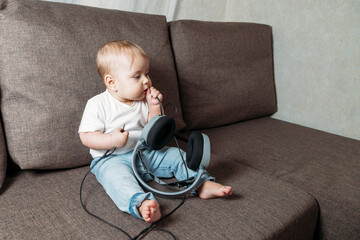 little baby girl holding in hands big headphones.