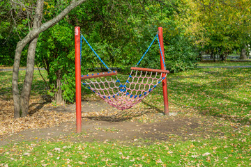 Fototapeta na wymiar Wicker hammock for rest and relaxation among the autumn trees in the city park