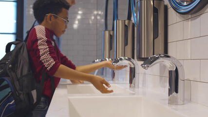Close up side view of diverse school pupils washing hands in lavatory © nimito