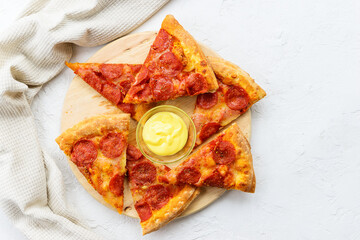 Slices of pepperoni pizza with sauce on a wooden board. Horizontal orientation, top view.