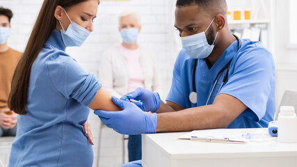 Pregnant Lady In Mask Receiving Coronavirus Vaccine Injection In Hospital