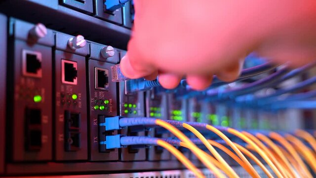 hand with network cables connected to servers in datacenter
