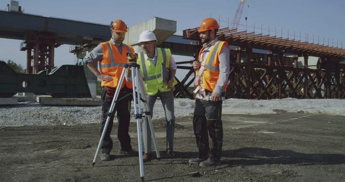 Male surveyors using theodolite together