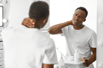 Obraz premium African Man Touching Aching Neck Suffering From Pain In Bathroom