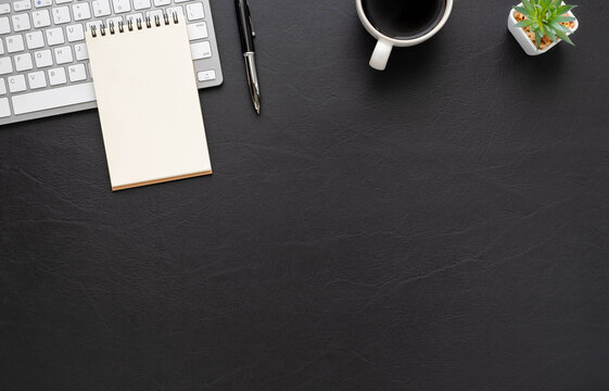 Black office desk table with keyboard, notebook and coffee cup with equipment office supplies. Business and finance concept. Workplace, Top view flat lay with blank copy space.