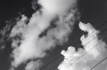 Gray sky and white clouds, power wires. Black and white photo.