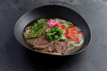 Traditional vietnamese pho bo soup in dark plate
