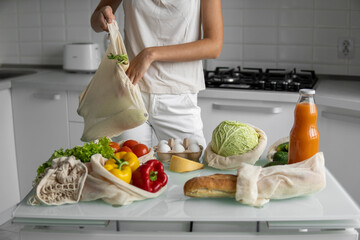 Woman hand holding Reusable eco textile grocery bag with vegetables and fruits. Zero waste and plastic free concept. Girl is holding mesh cotton shopper with vegetables.