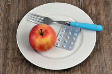 Pomme dans une assiette avec une fourchette et un blister de médicaments
