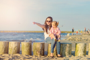 Happy mother and daughter in the park. Beauty nature scene with family outdoor lifestyle. Happy family resting together on the green grass, having fun outdoor. Happiness and harmony in family life