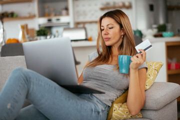 Young businesswoman at home makes a purchase on the Internet. Beautiiful woman on the laptop with credit card