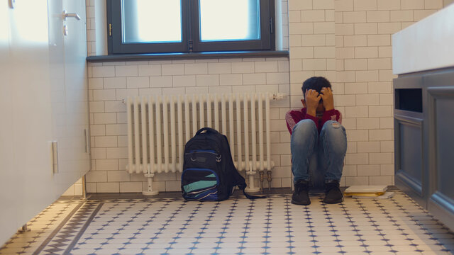Depressed african child abandoned in lavatory and leaning against wall.