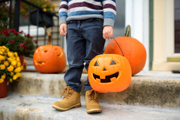Little boy at halloween party. Child holds a bucket shaped like a halloween pumpkin jack o lantern....
