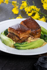 Fototapeta na wymiar Dong Po Rou (Dongpo pork meat) in a beautiful plate with green vegetable, traditional festive food for Chinese new year cuisine meal, close up.