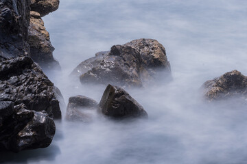 Stones are surrounded by a mist of sea water in a mystical atmosphere.