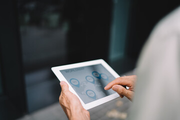 Unrecognizable man browsing tablet in street